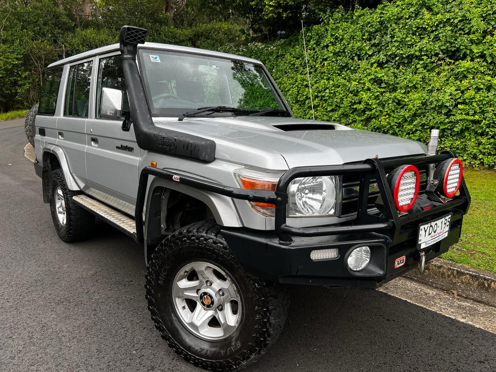 A Toyota LandCruiser 76 Series with a snorkel and bullbar, parked on a driveway.