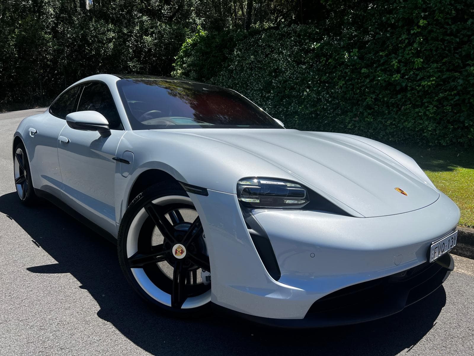 A Porsche Taycan in soft daylight, photographed from the front three-quarter angle.